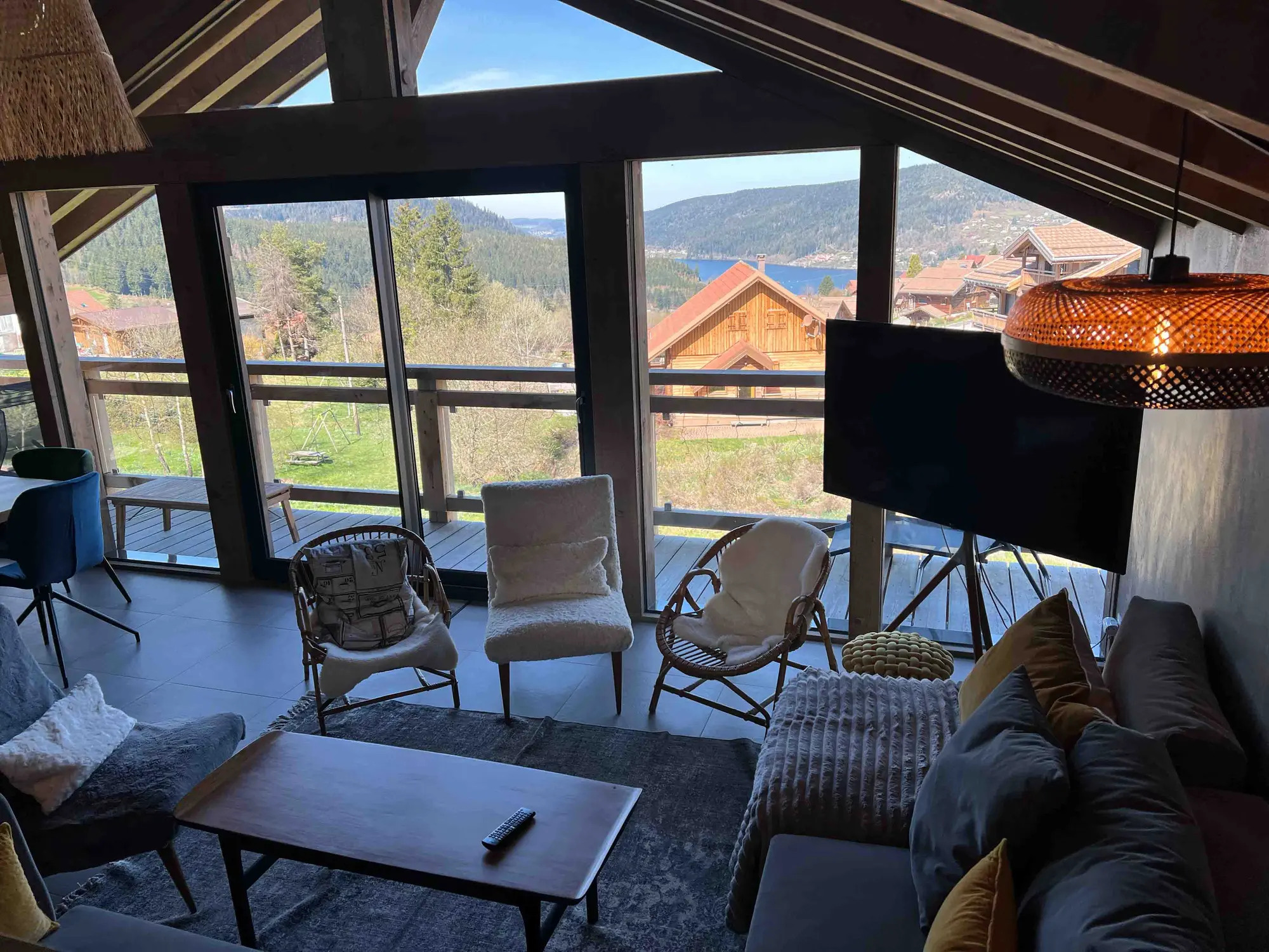 Salon du chalet ouvert sur les baies vitrées et la vue sur le lac